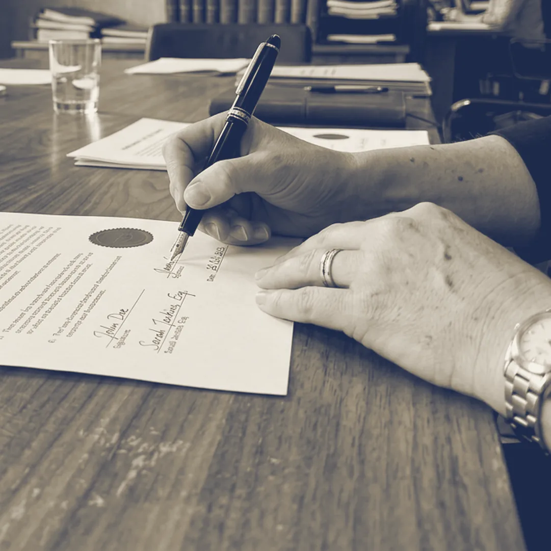 Manos firmando el acta de conciliación con pluma y sello